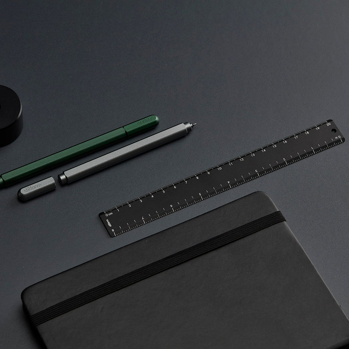 Lineal Warp Black im Vergleich mit Gelschreiber Titan Matt und Aurora Green auf dunklem Schreibtisch