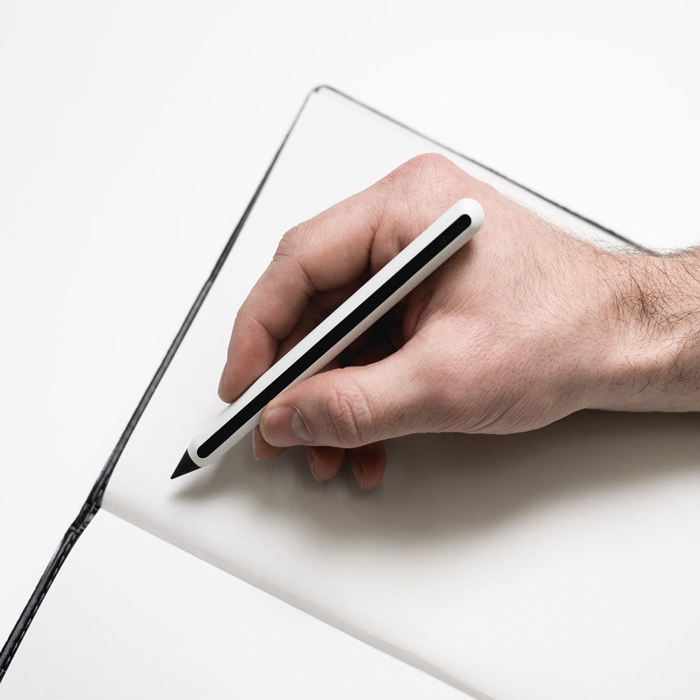 Hand schreibt mit AEON Aluminium-Bleistift in Polar White in ein weißes Notizbuch