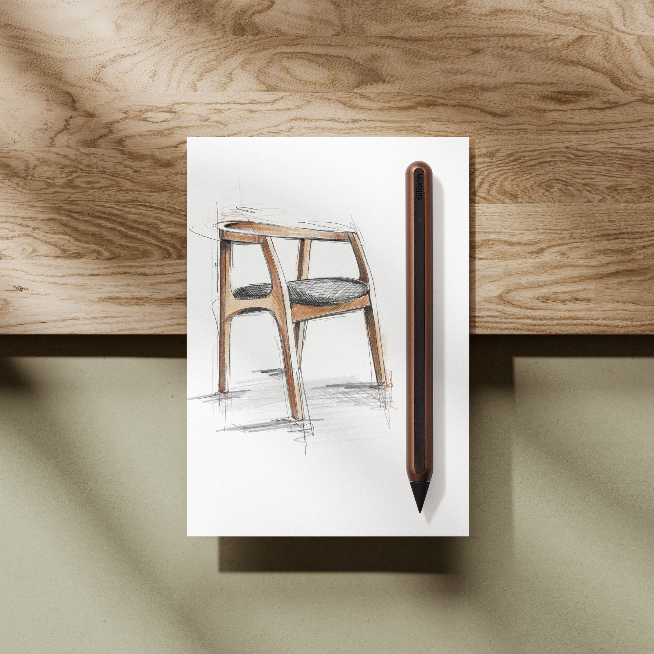 AEON Aluminium-Bleistift in Walnut Brown neben einer Skizze eines Holzstuhls auf weißem Papier, liegend auf Holztisch
