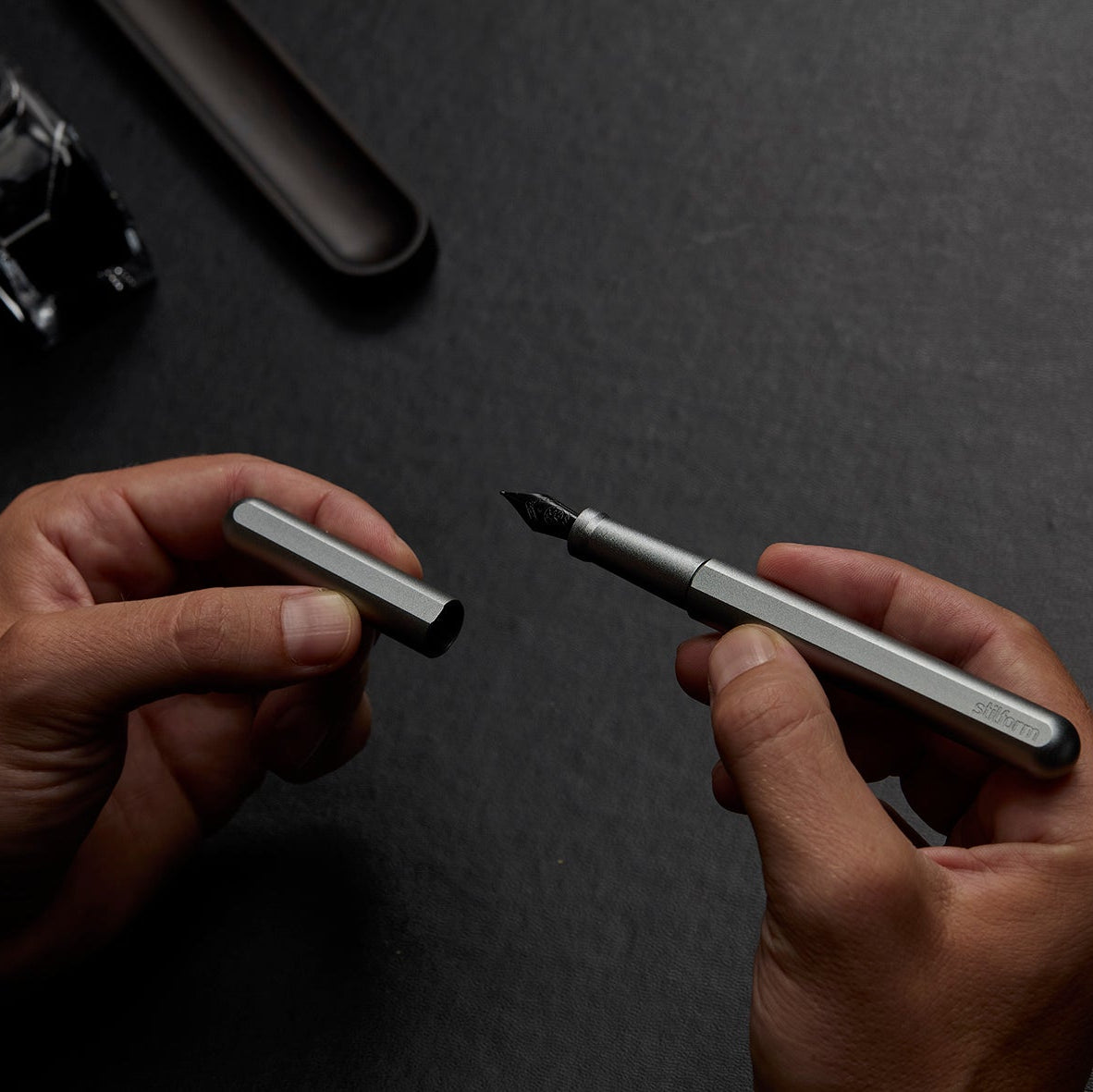 Füllfederhalter Ink Titan in matt mit schwarzer Stahlfeder in der Hand beim Abziehen der Kappe