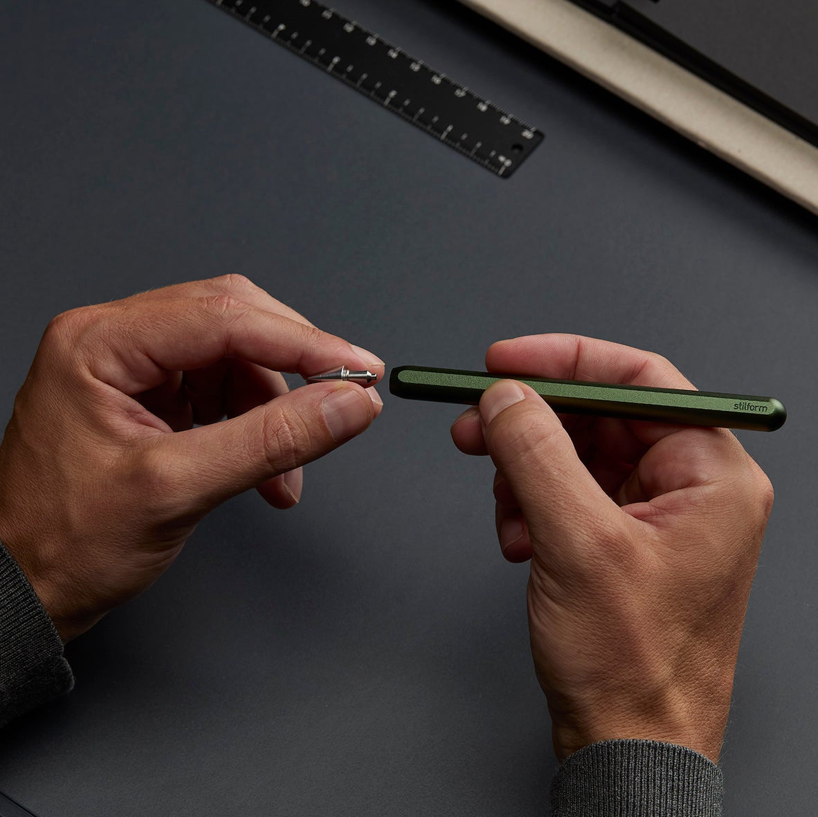 Person holding a green pen against a dark background